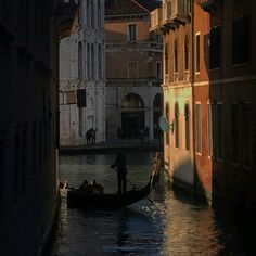 a gondola in the middle of a canal with buildings on both sides and people standing on it