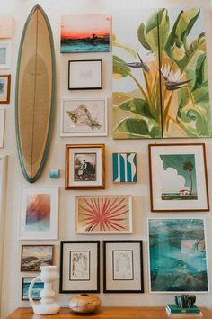 a surfboard mounted to the side of a wall filled with pictures and art pieces