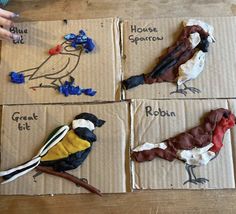 four birds are sitting on cardboard boxes with words painted on them and one bird is in the process of being made