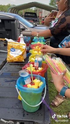 some people are sitting on the back of a truck with food in buckets next to them