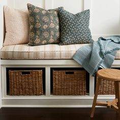 a white bench with baskets underneath it and a blanket on the bench next to it