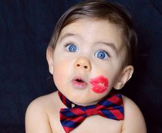 a baby wearing a red and blue bow tie with lipstick on it's cheek