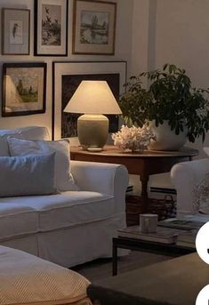 a living room filled with white furniture and pictures on the wall above it's coffee table