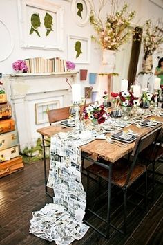 a dining room table is set with flowers, candles and newspapers on it as if for a special occasion