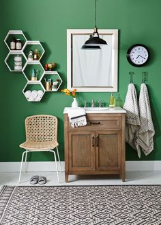 a bathroom with green walls and white accents, including a wooden vanity sink cabinet and shelving unit