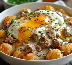 a bowl filled with tater tots covered in cheese and an egg on top