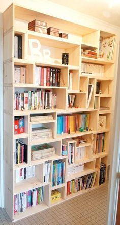 a bookshelf filled with lots of books on top of white shelves in a room