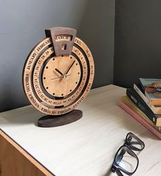 a wooden clock sitting on top of a table next to some books and eyeglasses