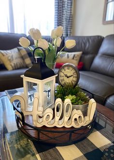 a coffee table topped with a vase filled with flowers and a clock on top of it