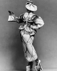 a black and white photo of a woman dressed in an unusual outfit with high heels