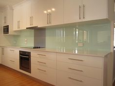 an empty kitchen with white cabinets and wood floors