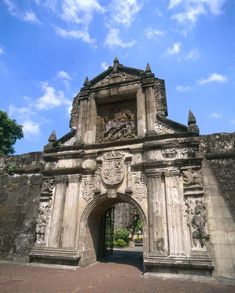 the entrance to an old stone building with statues on it's sides and a blue sky in the background