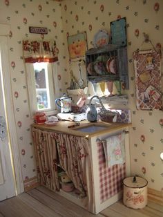 an old fashioned kitchen with floral wallpaper on the walls and wooden flooring in front of a window