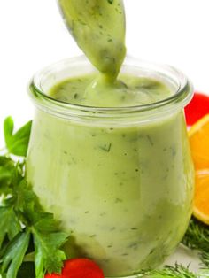 a jar filled with green liquid next to sliced oranges