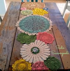 crocheted doily laid out on top of a wooden table with chairs in the background