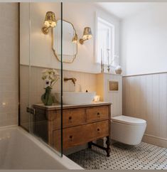 a white toilet sitting next to a bath tub under a window in a bathroom near a sink