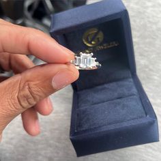 a person is holding an engagement ring in their hand and it's inside the box