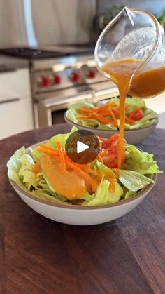 a person pouring dressing into a salad in a bowl with lettuce and carrots