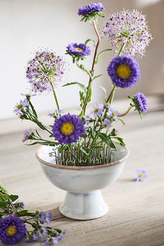 some purple flowers are in a white bowl