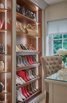 a closet with several pairs of shoes on shelves and a table in front of it