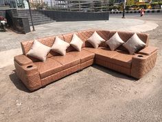 a brown couch sitting on top of a dirt field next to a parking lot filled with lots of pillows