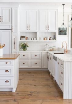 a kitchen with white cabinets and wooden floors