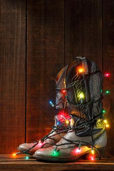 a pair of boots with christmas lights on them sitting in front of a wooden wall