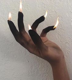 a person holding out their hand with three candles in it's palm, against a white wall