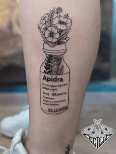 a woman's leg with a jar full of flowers on it and the words apidia written in black ink