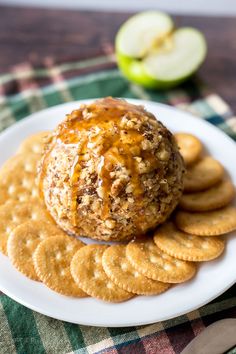 a cheese ball sitting on top of crackers with apples in the backgroud