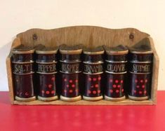 six spice jars in a wooden holder on a red table