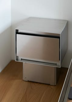 a metal box sitting on top of a wooden floor next to a wall and window