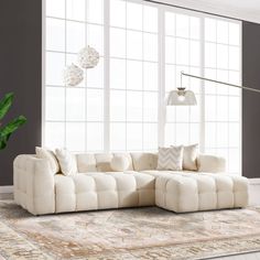 a living room with a large white sectional couch and two lamps hanging from the ceiling