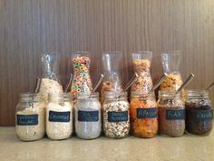 a row of glass jars filled with different types of food and cereals on top of a counter