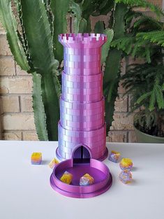 a purple tower with candy in it on a table next to some plants and a potted plant