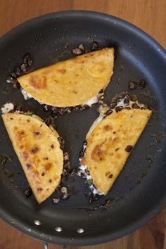 three quesadillas in a skillet on a wooden table