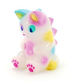 a small toy cat sitting on top of a white surface with pink and blue spots