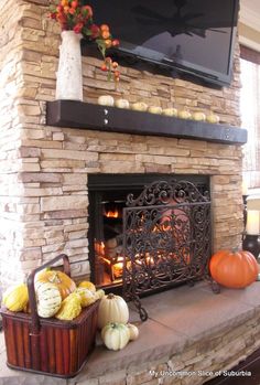 a fireplace with pumpkins, candles and a flat screen tv on it's mantle