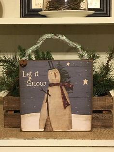 a wooden sign with a snowman on it sitting in front of a shelf filled with christmas decorations