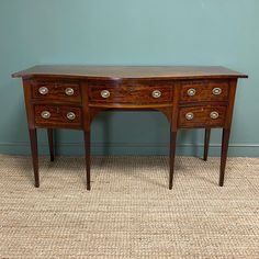 an old wooden desk with three drawers and two pulls on the top, against a blue wall