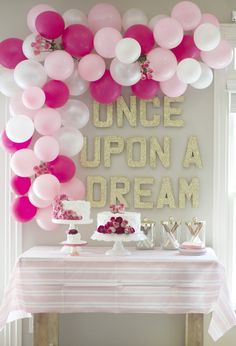 a table topped with lots of pink and white balloons next to a sign that says once upon a dream