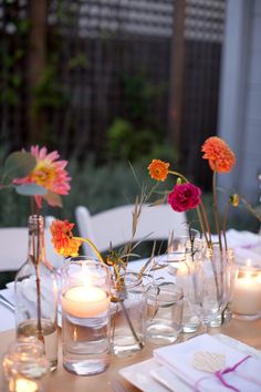 the table is set with candles and flowers in vases on top of each other