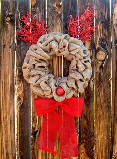 a burlock wreath with red berries hanging on a wooden fence, ready for the holiday season