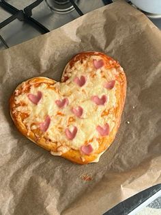 a heart shaped pizza sitting on top of a piece of wax paper next to a stove