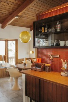 a kitchen area with wooden cabinets and white chairs, an orange lamp hanging from the ceiling