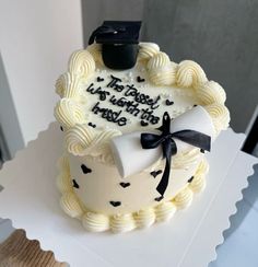 a white cake with black writing on it and a graduation cap sitting on top of it