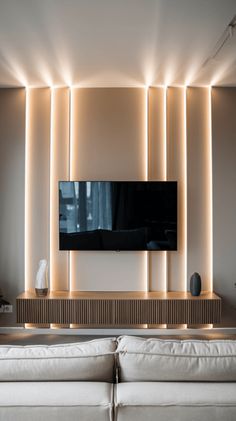 modern living room with white couches and large television on the back wall, illuminated by recessed lighting