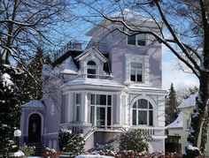 a large white house with snow on the ground and trees in front of it,