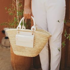 Handmade by craftswomen from our rural cooperative DOUM FOR WOMEN, our totes are made with impeccable craftsmanship and from high quality materials. Basket carryall bag as the perfect summer staple. Fresh, light and versatile tote with a rather rustic feel and a market vibe, ideal for strolling around in style from the beach to the city. This handwoven basket crafted from palm leaves is enriched with high-end classic vegan leather details, an exterior pocket and a removable canvas pouch with a z Luxury Straw Bucket Bag For Daily Use, Luxury Summer Bags With Bamboo Handle, Luxury Straw Bucket Bag For Women, Luxury Summer Bag With Bamboo Handle, Luxury Straw Bucket Bag For Beach, Luxury Straw Bag For Everyday Use In Spring, Luxury Tote Bucket Bag For Beach, Luxury Casual Straw Beach Bag, Luxury Casual Straw Bag For Everyday Use