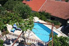 an aerial view of a swimming pool surrounded by greenery and red tiled roof tops